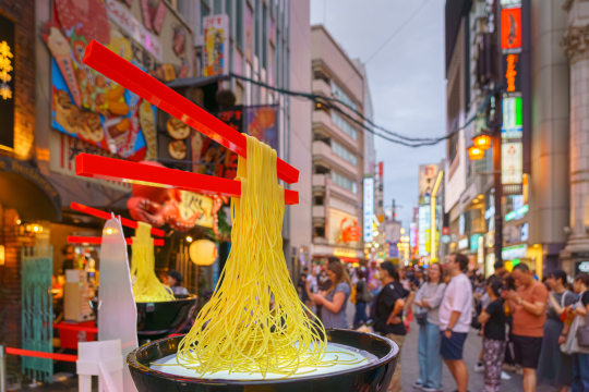 Schwebende St&auml;bchen &uuml;ber japansicher Sch&uuml;ssel mit Nudeln, als Deko in der japanischen Stadt Osaka 